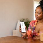 Shopper checking JCEX tracking on a phone at home next to a parcel