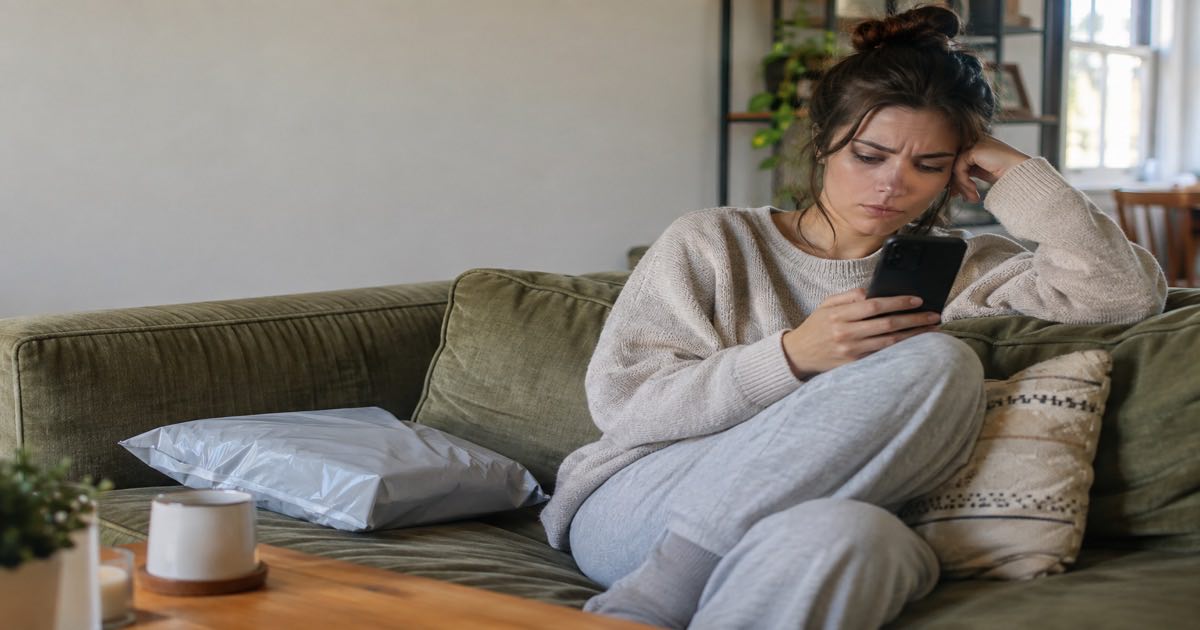 Frustrated young shopper checking her phone beside a fast-fashion poly mailer